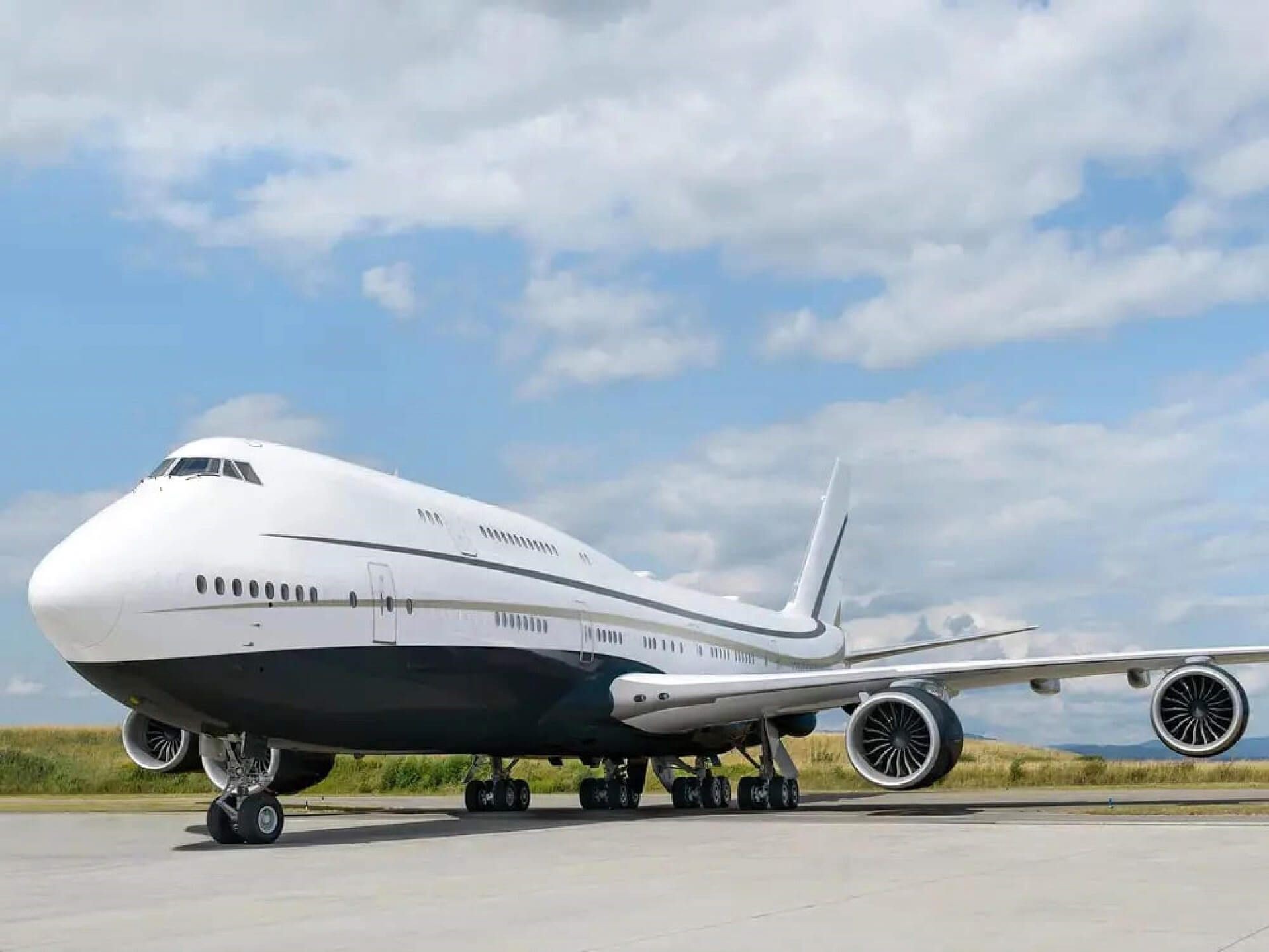 Large commercial airplane parked on an airport tarmac under a partly cloudy sky.