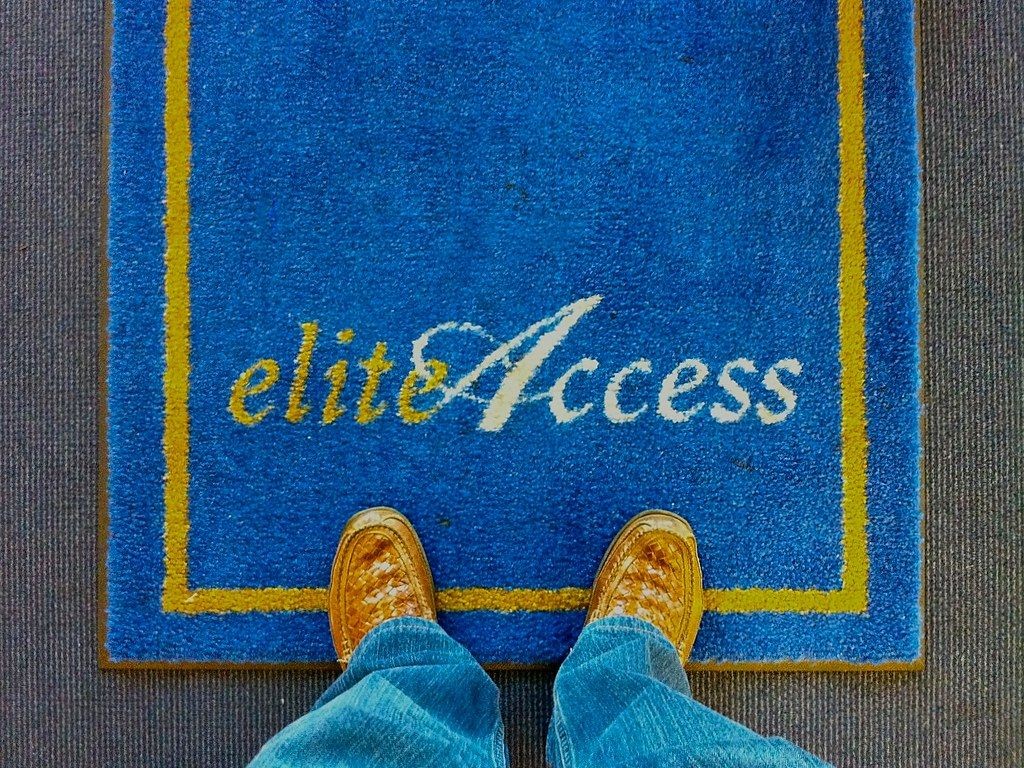 Person standing on a blue mat with 'elite Access' text, bordered by yellow lines.